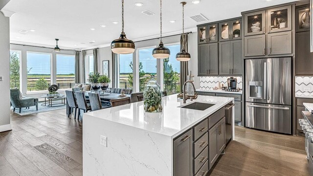 kitchen featuring a kitchen island with sink, stainless steel fridge with ice dispenser, sink, and a healthy amount of sunlight