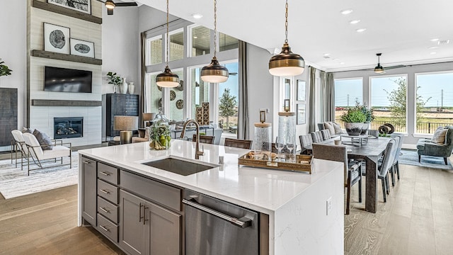 kitchen featuring light stone countertops, sink, light hardwood / wood-style flooring, decorative light fixtures, and a fireplace