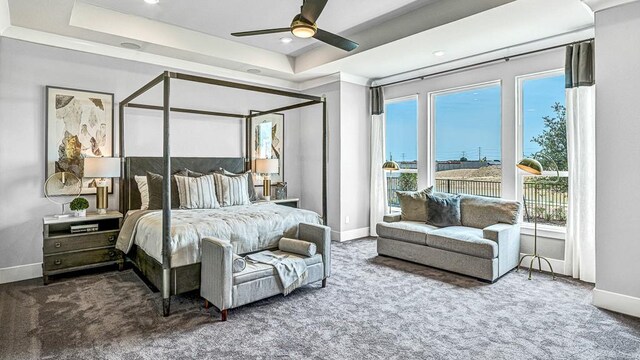 carpeted bedroom featuring ceiling fan and a tray ceiling