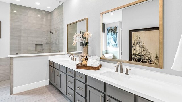 bathroom with tile patterned flooring, vanity, and tiled shower