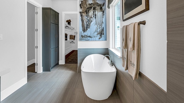 bathroom featuring a bathtub, tile walls, and tile patterned flooring