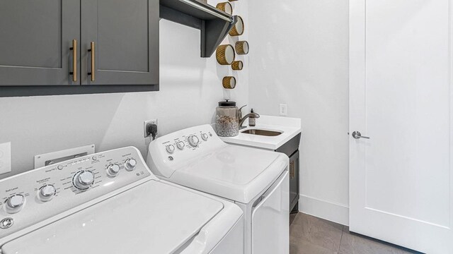 laundry area featuring tile patterned floors, washer and dryer, cabinets, and sink