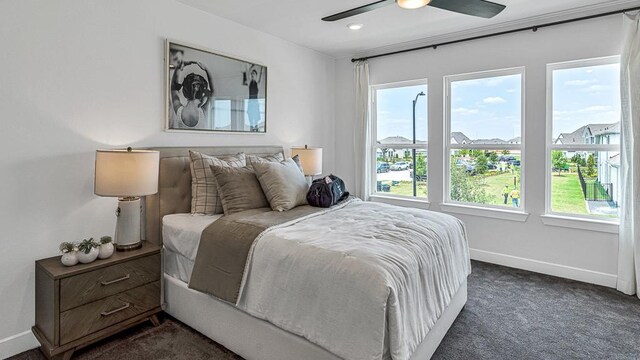 bedroom featuring multiple windows, dark colored carpet, and ceiling fan