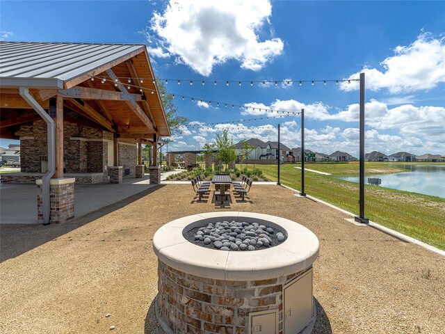 view of patio with a fire pit and a water view