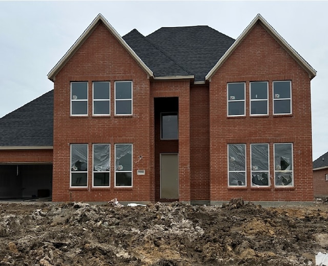 back of property with an attached garage, a shingled roof, and brick siding