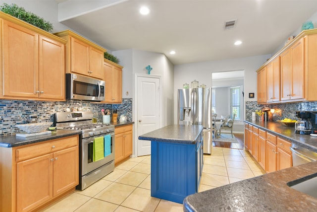 kitchen with backsplash, light tile patterned flooring, a kitchen island, and stainless steel appliances