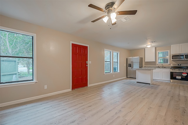 kitchen featuring white cabinets, plenty of natural light, light wood-type flooring, and appliances with stainless steel finishes