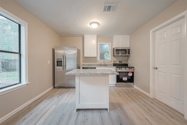 kitchen featuring light stone countertops, sink, light hardwood / wood-style flooring, white cabinets, and appliances with stainless steel finishes