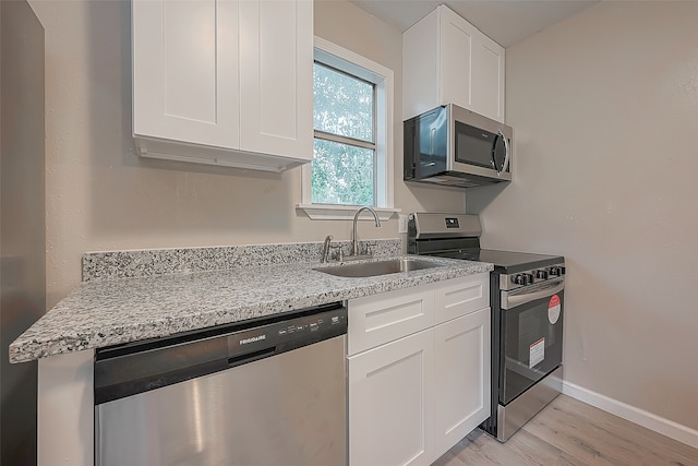 kitchen with white cabinets, sink, light hardwood / wood-style flooring, light stone counters, and stainless steel appliances