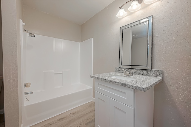 bathroom with washtub / shower combination, vanity, and hardwood / wood-style flooring