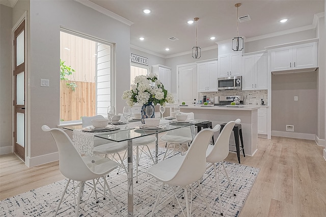 dining space featuring light hardwood / wood-style floors and crown molding