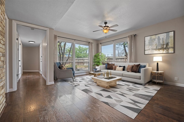 living room featuring dark hardwood / wood-style floors, ceiling fan, and a textured ceiling