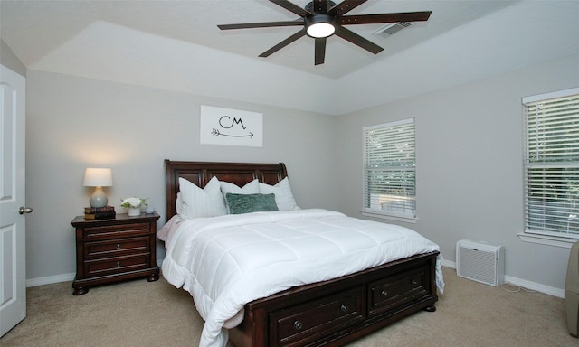 carpeted bedroom featuring multiple windows, a raised ceiling, and ceiling fan