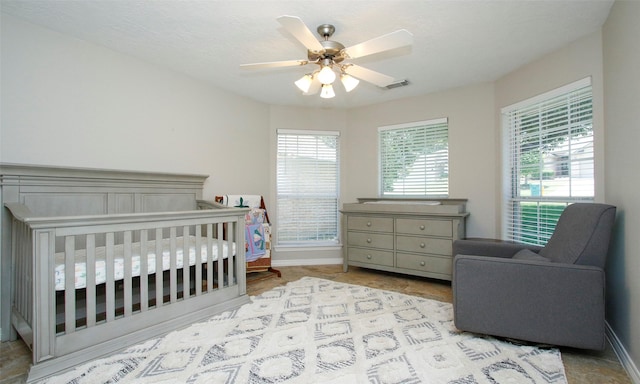 bedroom featuring a nursery area and ceiling fan