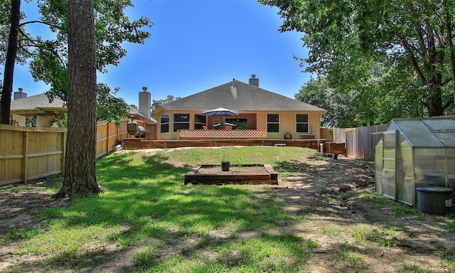 rear view of property with a wooden deck, an outdoor structure, and a yard