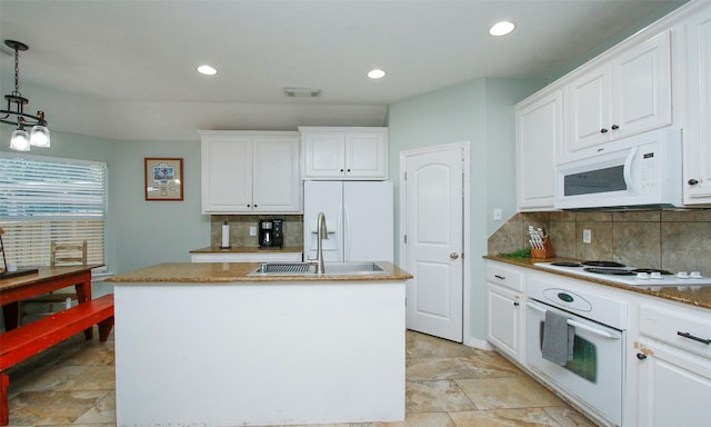 kitchen featuring white appliances, a kitchen island with sink, hanging light fixtures, and white cabinets