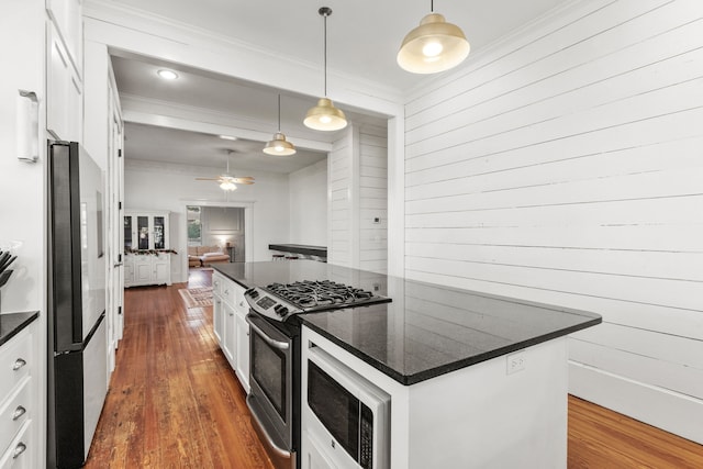 kitchen featuring white cabinetry, stainless steel appliances, dark hardwood / wood-style flooring, decorative light fixtures, and a kitchen island