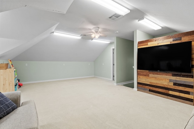 playroom featuring carpet flooring, ceiling fan, wooden walls, and vaulted ceiling