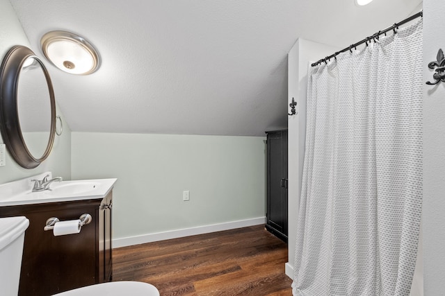 bathroom featuring curtained shower, wood-type flooring, vaulted ceiling, toilet, and vanity