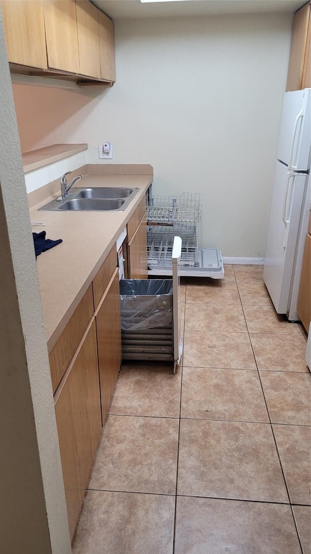 kitchen featuring light tile patterned floors, white fridge, and sink