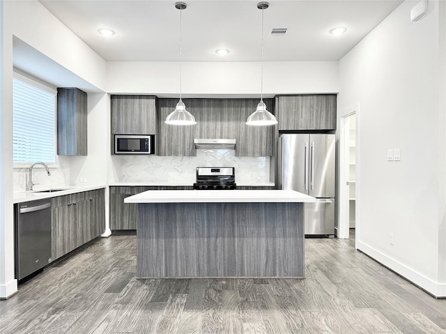 kitchen featuring pendant lighting, a center island, light wood-type flooring, and appliances with stainless steel finishes