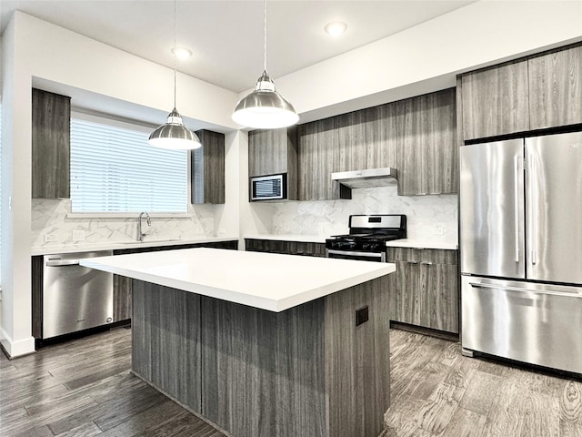 kitchen featuring a kitchen island, stainless steel appliances, extractor fan, and hardwood / wood-style flooring