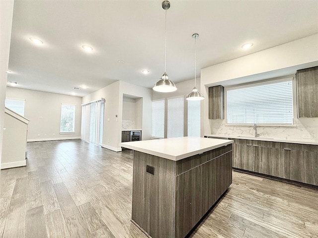 kitchen featuring backsplash, sink, a center island, and light hardwood / wood-style flooring