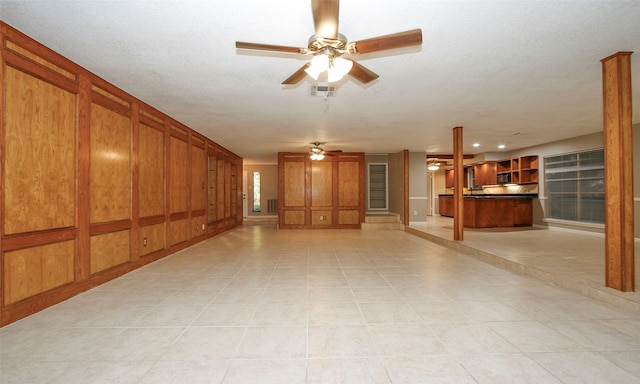 unfurnished living room featuring ceiling fan, light tile patterned floors, and a textured ceiling