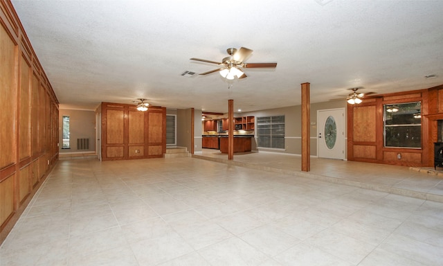 unfurnished living room with wood walls, light tile patterned floors, and a textured ceiling