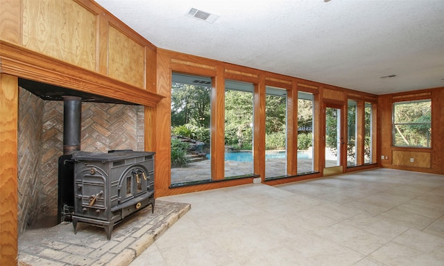 doorway to outside featuring a wood stove, wooden walls, and plenty of natural light