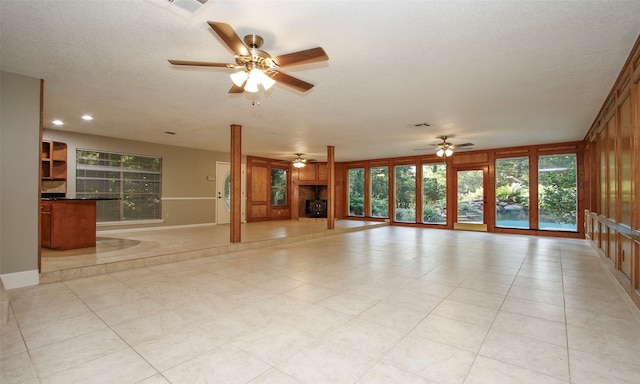 unfurnished living room with ceiling fan, a healthy amount of sunlight, light tile patterned floors, and a textured ceiling