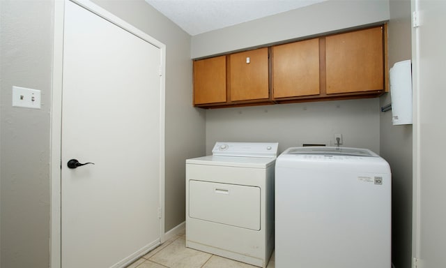 laundry area featuring light tile patterned flooring, cabinets, and washing machine and dryer