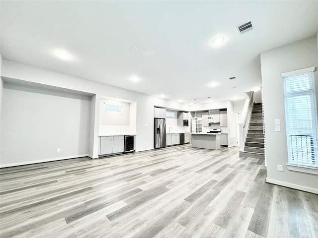 unfurnished living room featuring light wood-type flooring and wine cooler