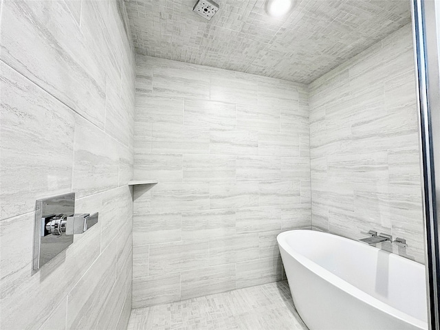 bathroom featuring a washtub and tile walls