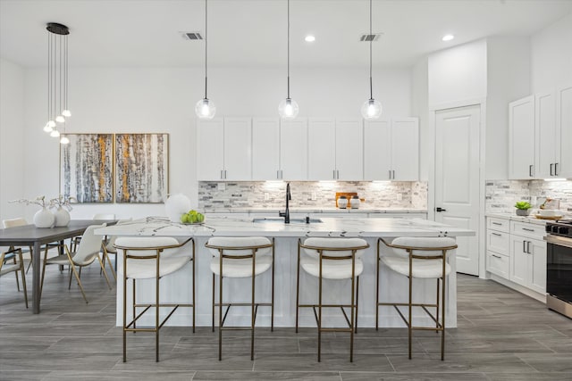 kitchen featuring an island with sink, sink, and decorative light fixtures