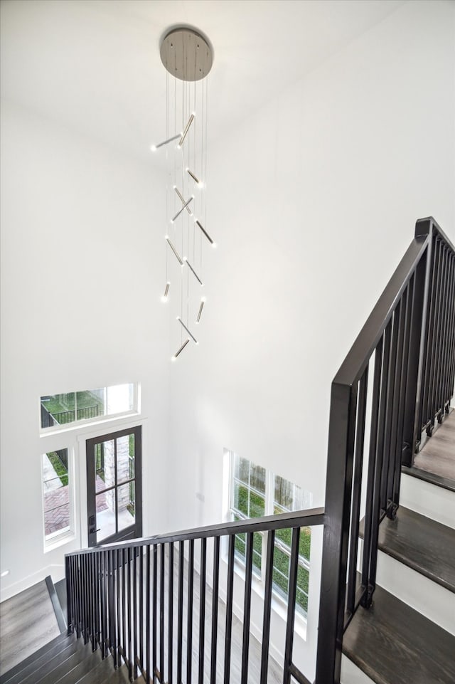 stairway with hardwood / wood-style flooring and a high ceiling