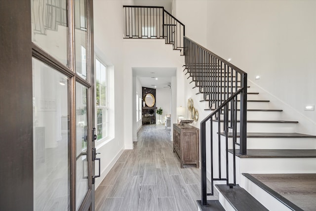 entrance foyer with a towering ceiling, light hardwood / wood-style flooring, and french doors