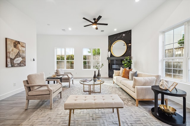 living room featuring ceiling fan, a fireplace, and light hardwood / wood-style floors