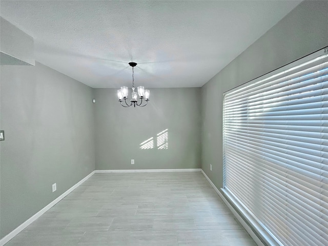 unfurnished room with a textured ceiling and an inviting chandelier