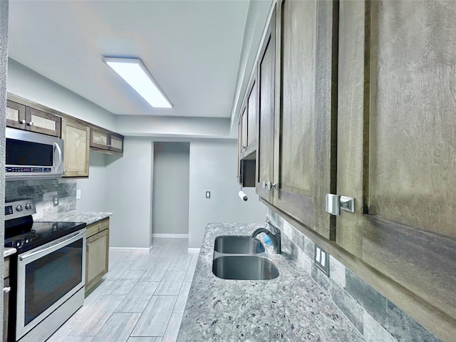 kitchen featuring light stone countertops, stainless steel appliances, and sink