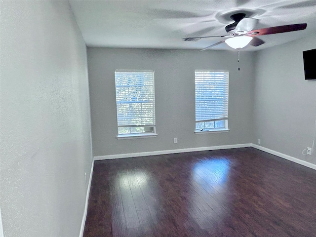 unfurnished room featuring plenty of natural light, ceiling fan, and dark wood-type flooring