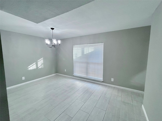 spare room featuring an inviting chandelier, a textured ceiling, and light wood-type flooring