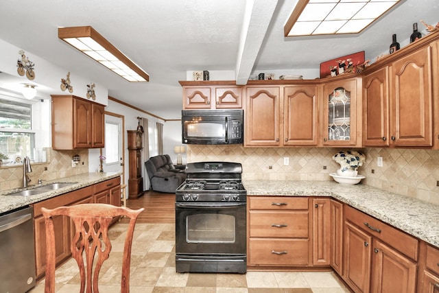 kitchen with backsplash, light stone countertops, sink, and black appliances