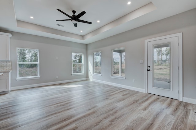 unfurnished living room featuring a healthy amount of sunlight and a raised ceiling