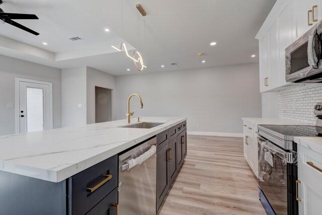 kitchen featuring a center island with sink, sink, light hardwood / wood-style flooring, appliances with stainless steel finishes, and white cabinetry