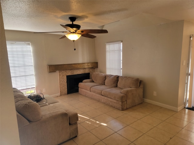 living room with a fireplace, light tile patterned floors, a textured ceiling, and ceiling fan