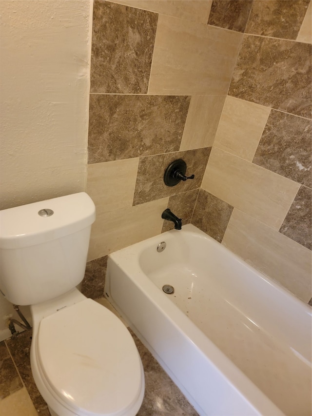 bathroom with tiled shower / bath, tile walls, and toilet