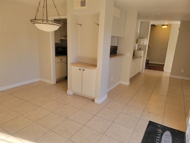 kitchen featuring white cabinets, decorative light fixtures, and light tile patterned flooring