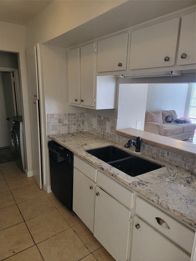 kitchen with washer / dryer, sink, light tile patterned floors, and black dishwasher