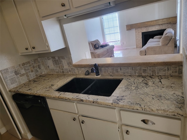 kitchen with light stone countertops, tasteful backsplash, sink, dishwasher, and white cabinetry